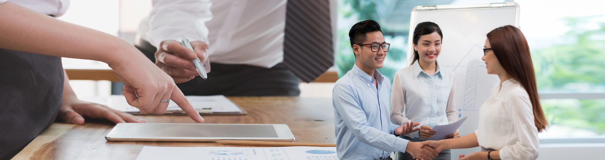 employees gesturing to a tablet and shaking hands with colleagues in the workplace